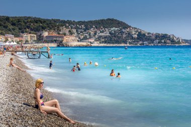 Güzel, Fransa - 23 Ağustos 2015: Turistler sahilde güzel havanın tadını çıkarıyorlar. Sahil ve liman bulvarı, Promenade des Anglais, neredeyse tüm yıl dolu..