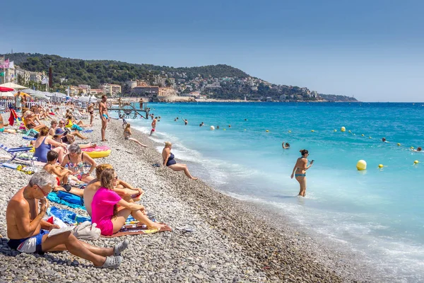Güzel, Fransa - 23 Ağustos 2015: Turistler sahilde güzel havanın tadını çıkarıyorlar. Sahil ve liman bulvarı, Promenade des Anglais, neredeyse tüm yıl dolu..