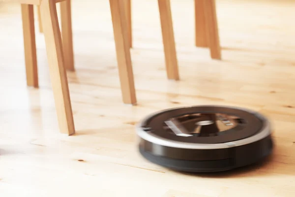 Роботизированный пылесос на ламинированном деревянном полу — стоковое фото