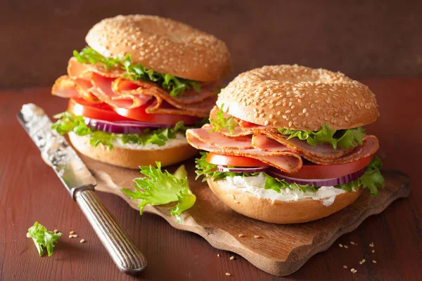 Skinksmörgås på bagel med cream ost tomat lök — Stockfoto