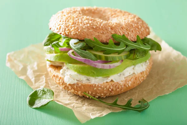 Sanduíche de abacate em bagel com creme de queijo cebola pepino arugu — Fotografia de Stock