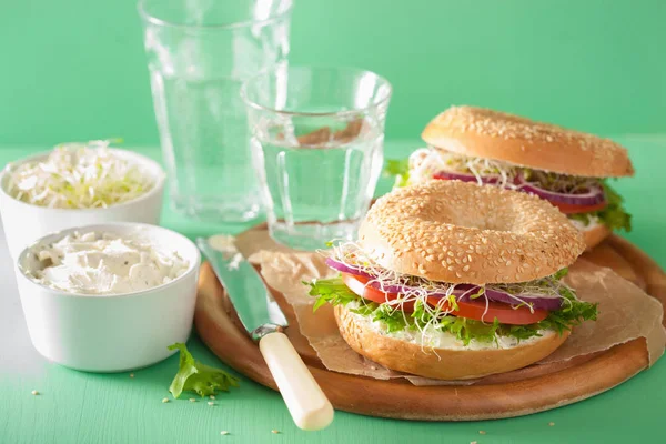 Tomat sandwich på bagel med flødeost løg salat lucerne - Stock-foto