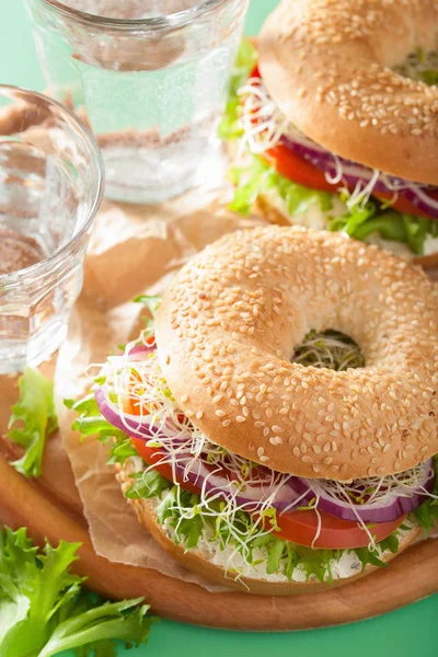 Tomat sandwich på bagel med flødeost løg salat lucerne - Stock-foto