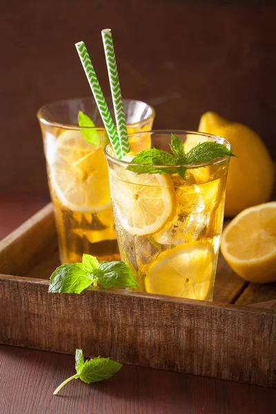 Chá de gelo com limão e hortelã no fundo rústico escuro — Fotografia de Stock
