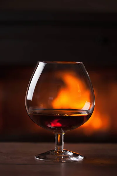 Un vaso de coñac frente a la chimenea — Foto de Stock