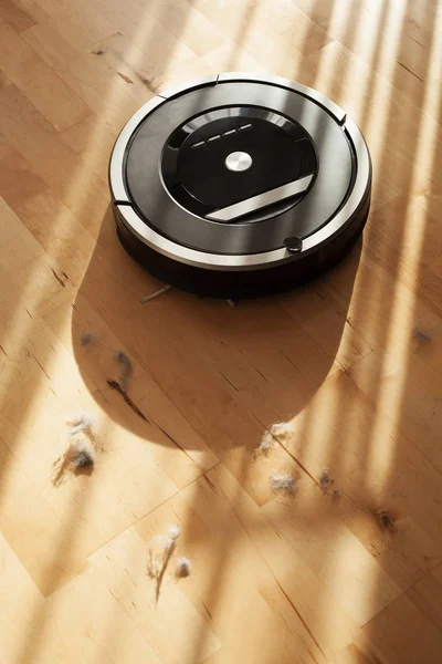 Роботизированный пылесос на ламинированном деревянном полу — стоковое фото