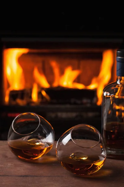 A glass of cognac in front of fireplace — Stock Photo, Image