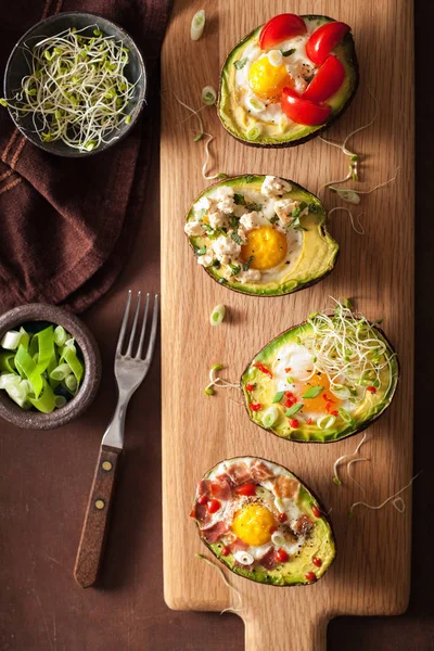 Яйца, приготовленные в авокадо с беконом, сыром, помидорами и люцерной — стоковое фото