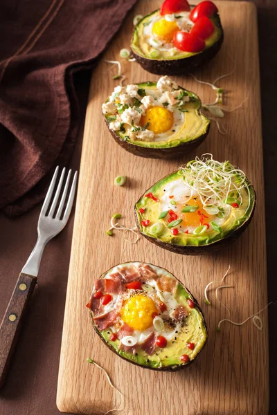 Яйца, приготовленные в авокадо с беконом, сыром, помидорами и люцерной — стоковое фото