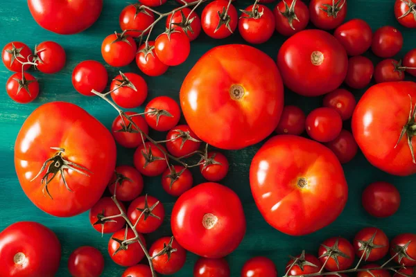 Různé rajčata na dřevěné pozadí — Stock fotografie