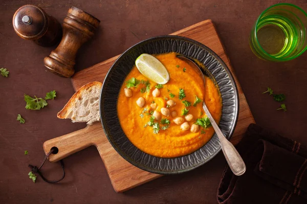 Sopa de grão de bico de cenoura cremosa no fundo rústico escuro — Fotografia de Stock