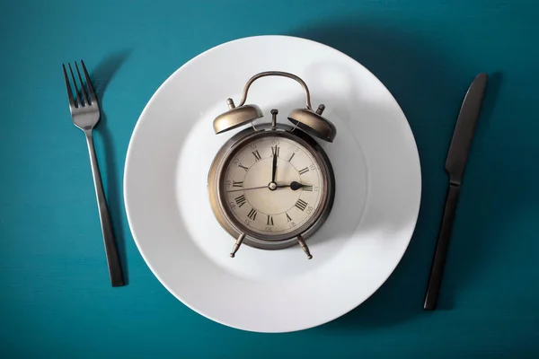 間欠的な断食ケトジェネティックな食事減量の概念です プレートと目覚まし時計の上でナイフとフォークを — ストック写真