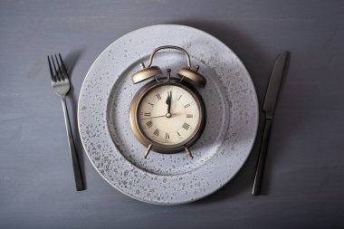 Perhiz konsepti, ketojenik diyet, kilo kaybı. çatal ve bıçak tabakta ve çalar saat