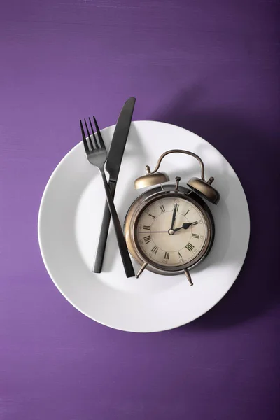 间歇性禁食的概念 产茶饮食 体重减轻 叉子和刀叉交叉在盘子和闹钟上 — 图库照片