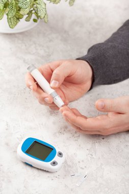 man hands using lancet on finger to check blood sugar or ketones level by glucose meter. medicine diabetes keto diet health care at home clipart