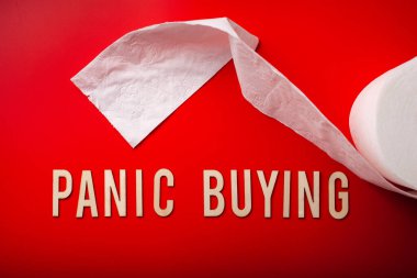 Panik halinde tuvalet kağıdı alıyor kırmızı arkaplan koronavirüs covid-19 'da ahşap harf yazıyor.