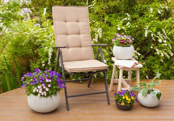 garden chair on terrace in sunlight, pansy flowers