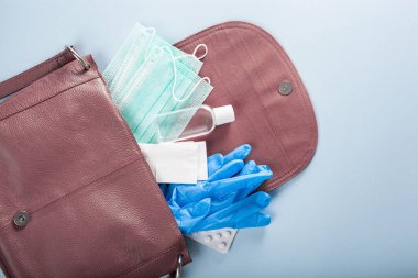 Koruyucu tıbbi maske, dezenfektan jeli ve pembe çantada eldivenler. Virüs ve bakterilere karşı koruyucu önlemler