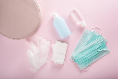 Koruyucu tıbbi maske, dezenfektan jeli ve pembe çantada eldivenler. Virüs ve bakterilere karşı koruyucu önlemler