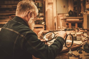 Senior restorer working with antique decor element  clipart