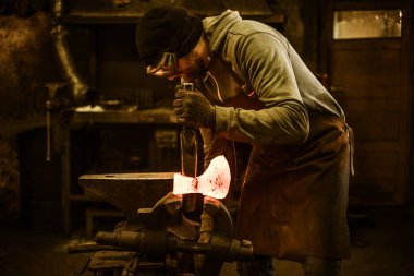 Blacksmith forging the molten metal  clipart