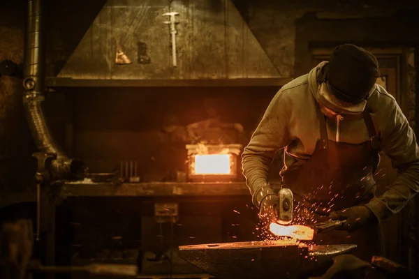 Blacksmith with brush handles the molten metal — Stock Photo, Image