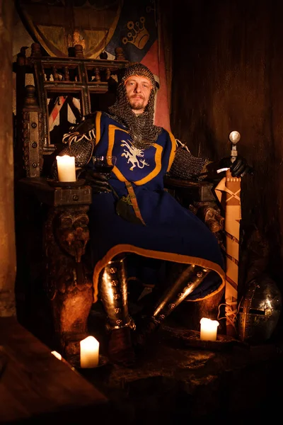 Medieval king on throne in ancient castle interior.