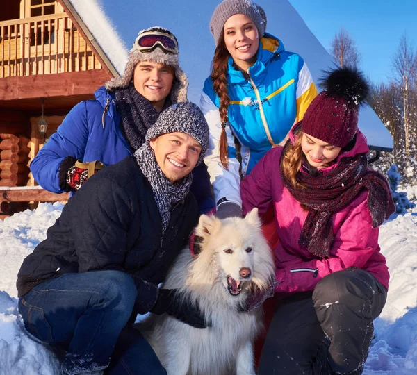 Amici allegri con cane trascorrono le vacanze invernali insieme a cottage di montagna — Foto Stock