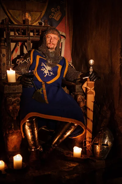 Medieval king on throne in ancient castle interior.