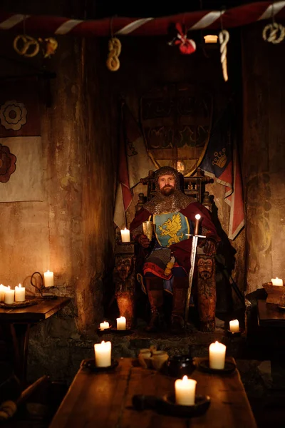 Middeleeuwse koning op de troon in oude kasteel-interieur. — Stockfoto