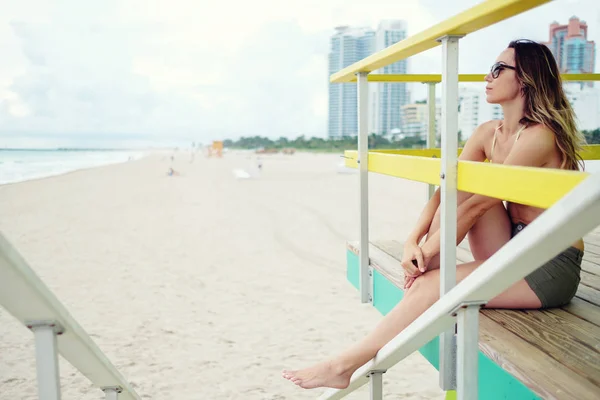 Vacker kvinna i bikini som sitter vid lifeguard station — Stockfoto
