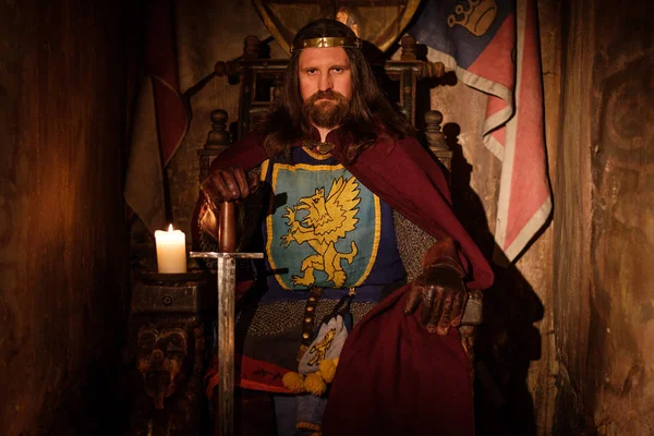 Medieval king on throne in ancient castle interior. — Stock Photo, Image