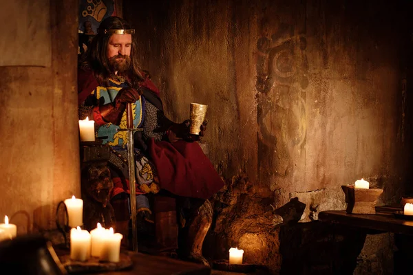 Medieval king on throne in ancient castle interior. — Stock Photo, Image