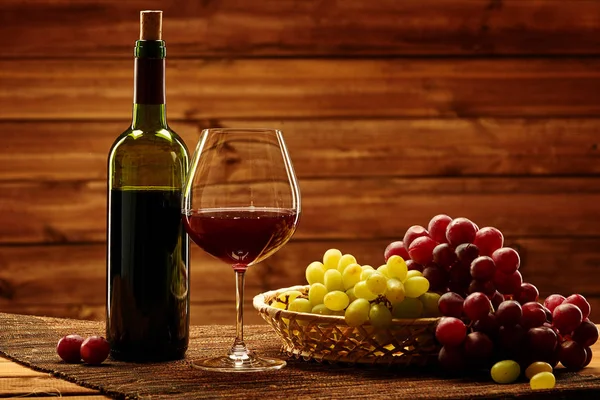 Bottle of red wine, glass and grape in basket — Stock Photo, Image