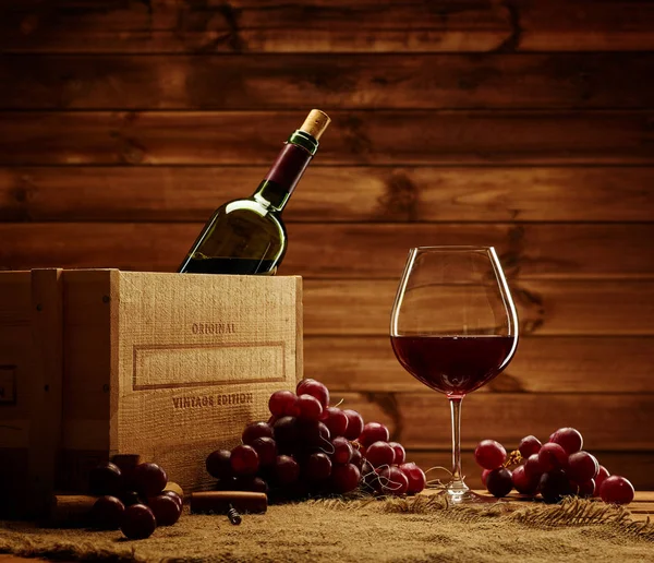 Garrafa, vidro e uva vermelha em uma mesa de madeira — Fotografia de Stock