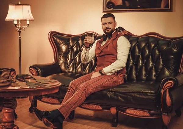 Extravaganter stylischer Mann mit einem Glas Whisky — Stockfoto