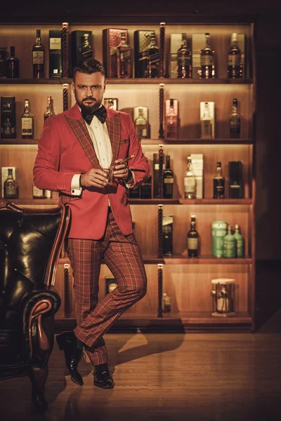 Экстравагантный стильный мужчина со стаканом виски — стоковое фото