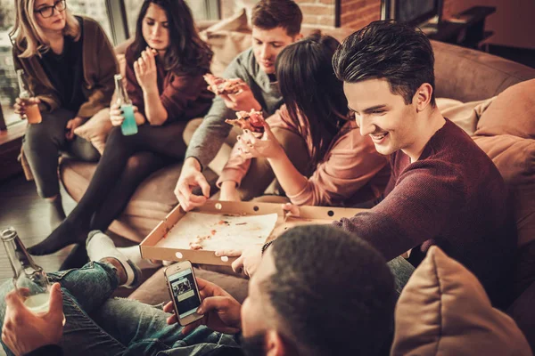 Groep multi etnische jonge vrienden eten van pizza in interieur — Stockfoto
