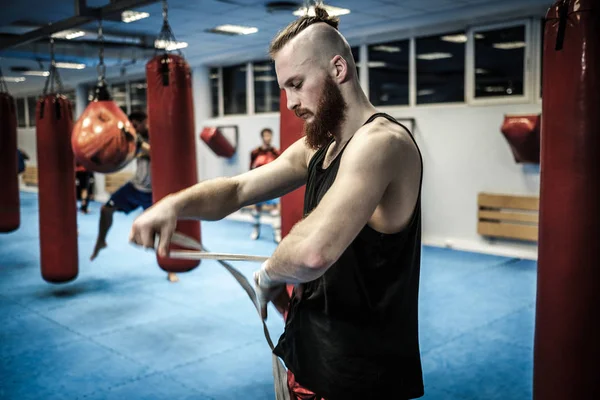 Lutador se preparando para o treinamento, envolvendo as mãos com invólucros de boxe — Fotografia de Stock