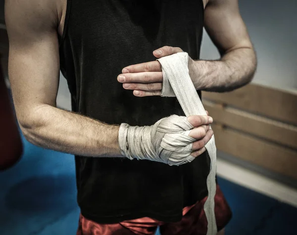 Combatiente preparándose para el entrenamiento, envolviendo las manos con envolturas de boxeo — Foto de Stock