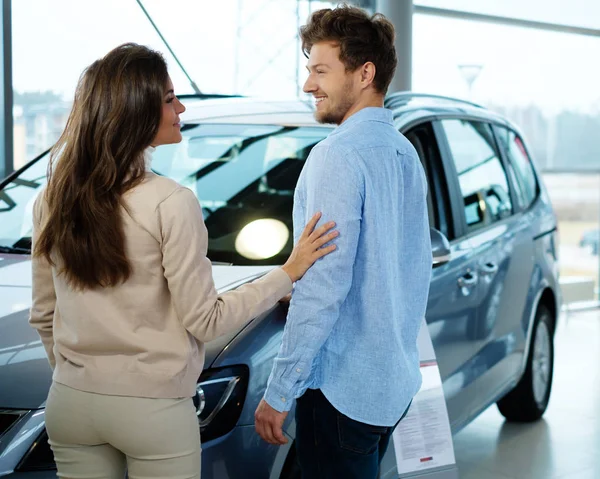 Casal procurando um carro novo no showroom concessionária — Fotografia de Stock