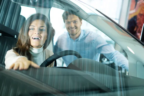 Pareja buscando un coche nuevo en la sala de exposición concesionario —  Fotos de Stock