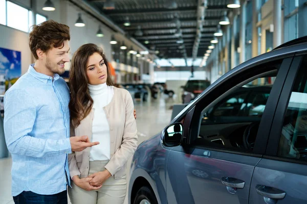 Pareja buscando un coche nuevo en la sala de exposición concesionario — Foto de Stock