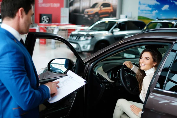 Mooie jonge vrouw koopt een auto in de dealer saloon — Stockfoto
