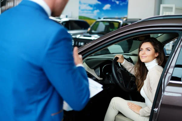 Mujer joven compra un coche en el salón de concesionarios — Foto de Stock