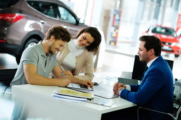 Verkäufer übergibt Schlüssel des neuen Autos an junges Paar — Stockfoto