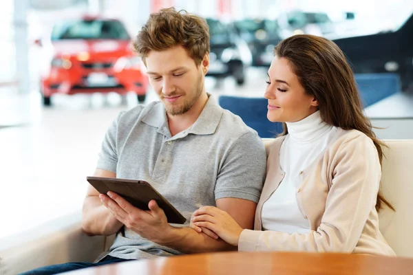 Couple looking a new car at the dealership showroom — Stock Photo, Image