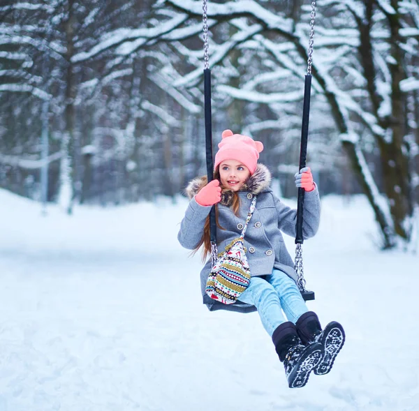 Charmantes kleines Mädchen auf Schaukel im verschneiten Winter — Stockfoto