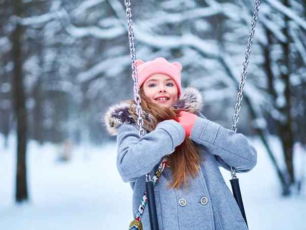 Charming little girl on swing in snowy winter — Stock Photo, Image