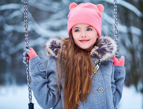 Charmantes kleines Mädchen auf Schaukel im verschneiten Winter — Stockfoto